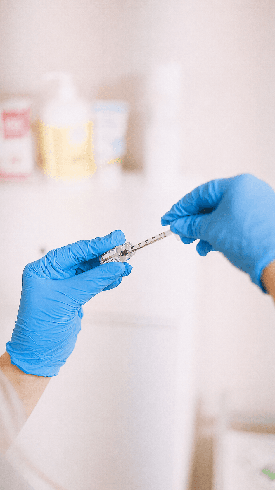 Manos con guantes preparando un medicamento en una jeringa a partir de un vial en un entorno clínico
